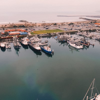 Aerial view of a marina with parked boats and nearby beachfront buildings.