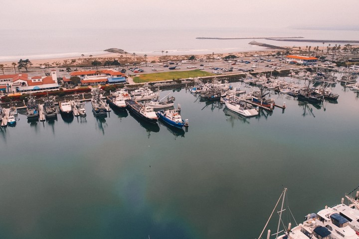 Aerial view of a marina with parked boats and nearby beachfront buildings.
