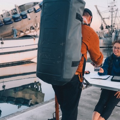 Person at table receives payment from another person near boats at a marina.