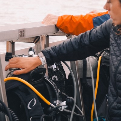 Person on boat preparing scuba diving equipment.