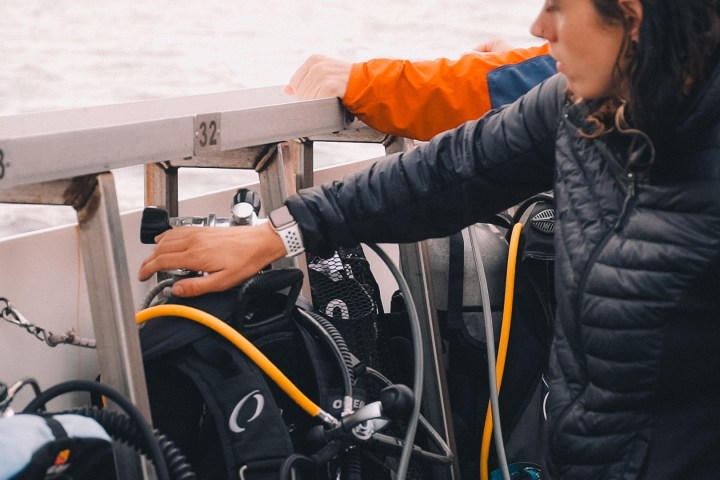 Person on boat preparing scuba diving equipment.