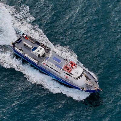 Aerial view of a white and blue boat navigating through waves on a vast body of water.