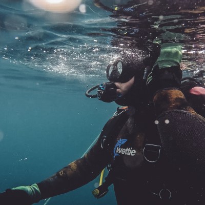 Scuba diver underwater using gear with bubbles around.