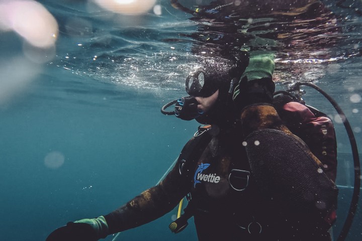 Scuba diver underwater using gear with bubbles around.